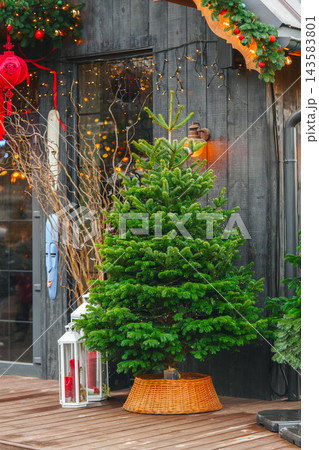 Christmas tree decorated with delicate lights outside of modern storefront with warm golden bokeh Christmas tree decorated with delicate lights outside of modern storefront with warm golden bokeh 143583801