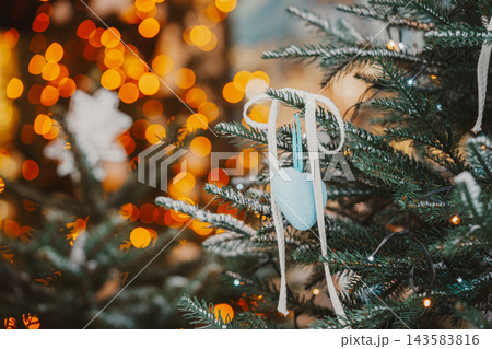 Snowy Christmas tree branches with blue heart and ribbon on glowing fairy lights bokeh background Snowy Christmas tree branches with blue heart and ribbon on glowing fairy lights bokeh background 143583816
