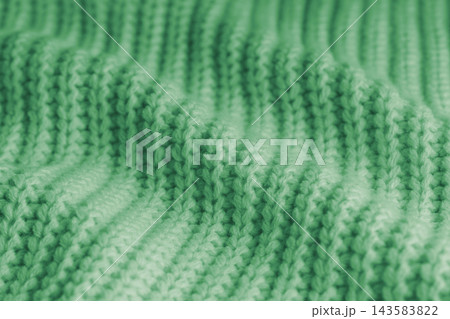 Soft green knitted sweater texture with chunky yarn and raised stitches, waves and gentle folds 143583822