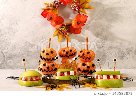 Scary monsters and ghosts made of apples and tangerines on old concrete background, cafe and menu advertising, restaurant business card, Halloween food concept, holiday meal idea for kids and adults. Scary monsters and ghosts made of apples and tangerines on old concrete background, cafe and menu advertising, restaurant business card, Halloween food concept, holiday meal idea for kids and adults. 143583872