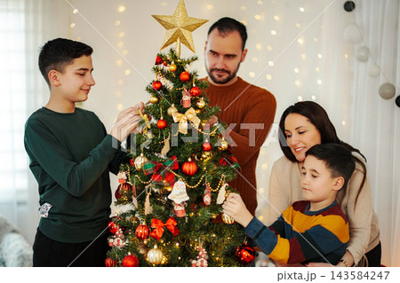 Family decorating Christmas tree together for holiday celebration 143584247