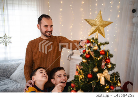 Family decorating Christmas tree with children in living room 143584258