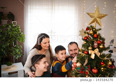 Family decorating Christmas tree together for winter holiday Family decorating Christmas tree together for winter holiday 143584270