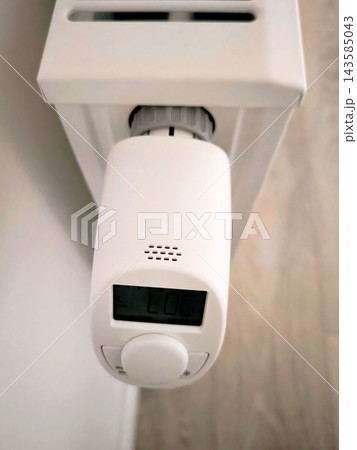 Digital thermostat on a white radiator with LOC and day of the week indicator. Top view. 143585043