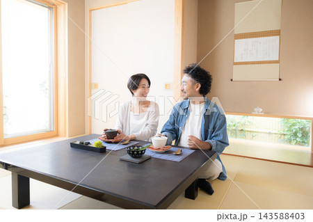 温泉旅館のような和室で座る、会話しながら旅行を楽しむ日本人夫婦の観光旅行や国内旅行の宿泊先イメージ 温泉旅館のような和室で座る、会話しながら旅行を楽しむ日本人夫婦の観光旅行や国内旅行の宿泊先イメージ 143588403
