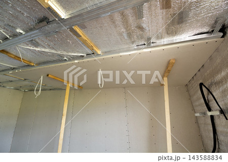 Room under construction with silver aluminum insulation foil and drywall on walls and ceiling. Room under construction with silver aluminum insulation foil and drywall on walls and ceiling. 143588834
