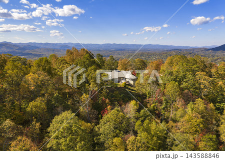 Residential homes overlooking colorful forested hills during peak fall season. Peaceful mountain landscape filled with brilliant autumn foliage. Residential homes overlooking colorful forested hills during peak fall season. Peaceful mountain landscape filled with brilliant autumn foliage. 143588846