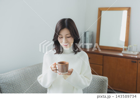 リビングでコーヒーを飲むミドル女性 リビングでコーヒーを飲むミドル女性 143589734