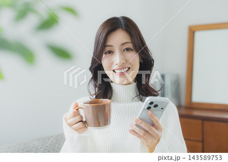 リビングでコーヒーを飲むミドル女性 リビングでコーヒーを飲むミドル女性 143589753