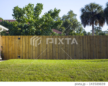 Wooden plank fence in Florida backyard. Timber fencing for grounds protection and privacy. Wooden plank fence in Florida backyard. Timber fencing for grounds protection and privacy. 143589839