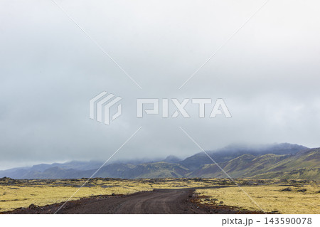 Icelandic volcanic landscape with moss and dirt road 143590078