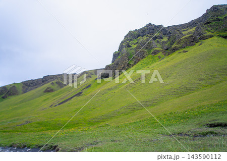 Green hillside and rocky mountain near Vik, Iceland 143590112