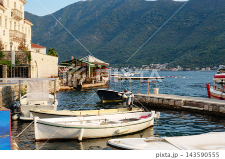 Boats in a harbor near a waterfront restaurant on a calm day with hills in the background Boats in a harbor near a waterfront restaurant on a calm day with hills in the background 143590555