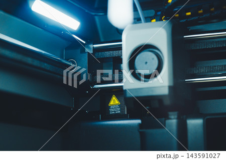 Working on 3D printer with laptop while preparing to print a project in a home office setting during daytime 143591027