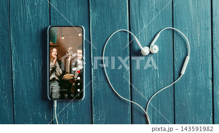 Social media chats and calls with friends using a phone and headphones on a wooden table 143591982