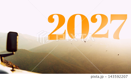 Large numbers in orange display the year 2027 with a landscape in the background showcasing mountains and a sunset Large numbers in orange display the year 2027 with a landscape in the background showcasing mountains and a sunset 143592207