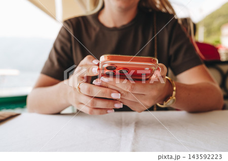 Woman using smartphone at outdoor cafe in daytime Woman using smartphone at outdoor cafe in daytime 143592223