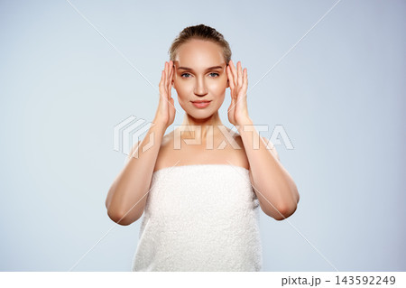 Woman applies facial treatment in a clean studio setting during daylight hours Woman applies facial treatment in a clean studio setting during daylight hours 143592249