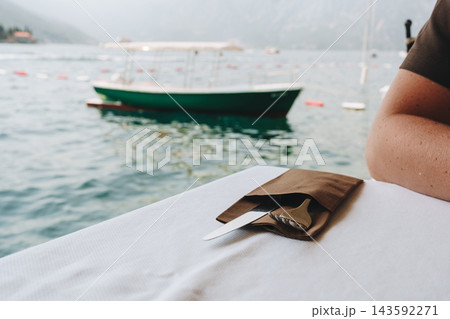 Lunch setting by the lake with a view of a boat and distant mountains 143592271