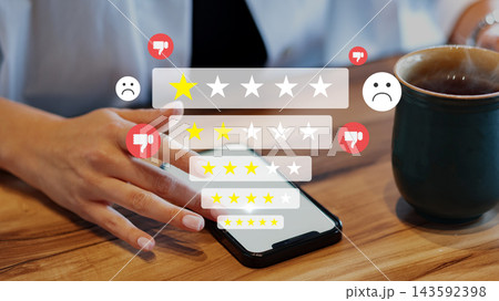 Person gives rating on mobile phone while sitting at table with a cup of coffee Person gives rating on mobile phone while sitting at table with a cup of coffee 143592398