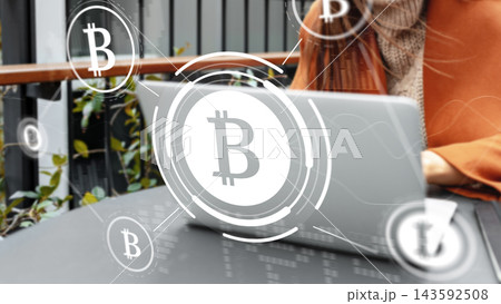Person using a laptop with bitcoin symbols around in a modern outdoor setting in daytime Person using a laptop with bitcoin symbols around in a modern outdoor setting in daytime 143592508