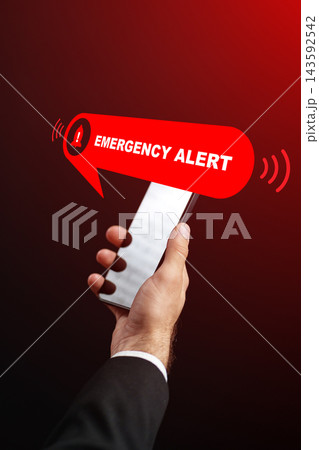 Emergency alert notification on a smartphone with a hand holding the device in a dark background Emergency alert notification on a smartphone with a hand holding the device in a dark background 143592542
