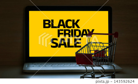 Black Friday sale displayed on a computer screen with a shopping cart next to it in a retail or online setting Black Friday sale displayed on a computer screen with a shopping cart next to it in a retail or online setting 143592624