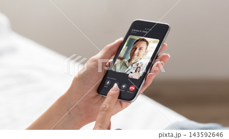 Person using smartphone for video call while sitting on bed 143592646