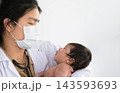 Asian doctor holding cute newborn baby in her arms for physical check up in clinic. 143593693