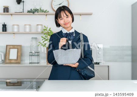 家のキッチンで通学用の保冷バッグにお弁当を入れる制服姿の女子高校生 家のキッチンで通学用の保冷バッグにお弁当を入れる制服姿の女子高校生 143595409