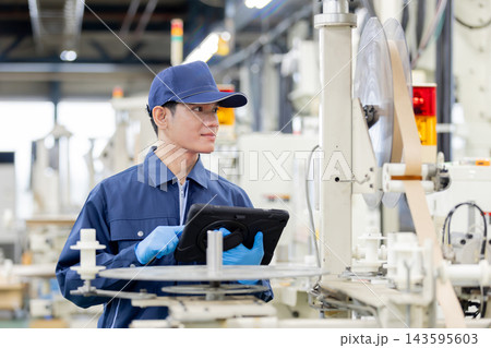 製造工場でタブレット端末を操作しながら働く外国人男性作業員 製造工場でタブレット端末を操作しながら働く外国人男性作業員 143595603