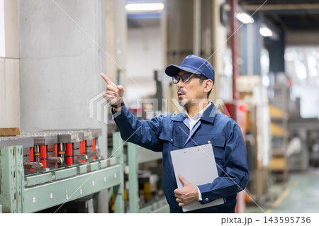 製造工場で金型の保管棚を指差し確認しながら設備管理を行うベテラン男性技術者 製造工場で金型の保管棚を指差し確認しながら設備管理を行うベテラン男性技術者 143595736