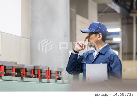 製造工場で金型を見ながら考え込むベテラン男性技術者・設備点検と品質管理のイメージ 143595738