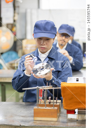 製造工場でライト付きルーペを使い精密金属部品の外観検査を行う若い男性技術者 製造工場でライト付きルーペを使い精密金属部品の外観検査を行う若い男性技術者 143595744