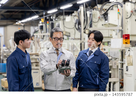 製造工場で外国人労働者に機械部品や自社製品の構造を説明する日本人社員・外国人材への技術指導と社員教育 143595787