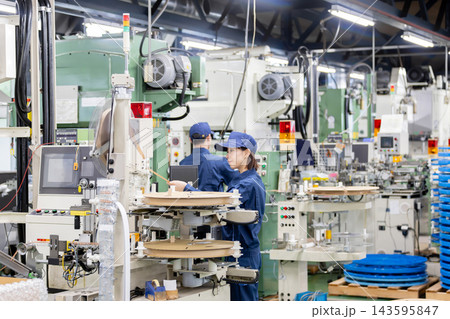 工場内で製造機械の点検と確認作業を行う若い男性作業員と製造スタッフたち 143595847