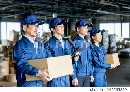 製造工場でタブレットや書類を持ち、前方を見つめる男女4人の作業員と外国人労働者 143595859