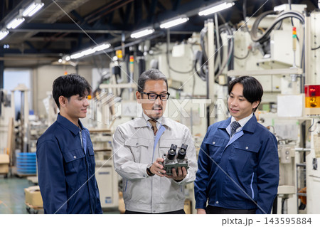 製造工場で外国人労働者に機械部品や自社製品の構造を説明する日本人社員・外国人材への技術指導と社員教育 143595884