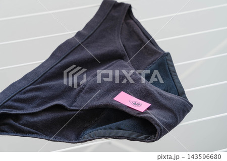 Dark period panties with an absorbent gusset lining drying on a white laundry rack. Reusable menstrual underwear for sustainable feminine hygiene and zero waste personal care. Dark period panties with an absorbent gusset lining drying on a white laundry rack. Reusable menstrual underwear for sustainable feminine hygiene and zero waste personal care. 143596680