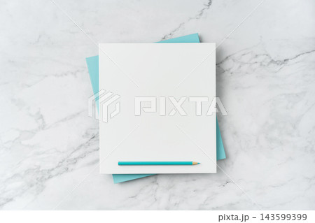 Top view of blank white and blue square greeting card with pencil mockup on marble background with copy space 143599399
