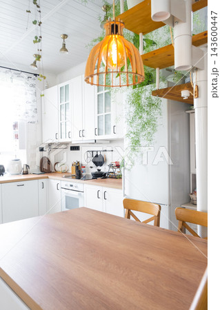 Cozy dining corner in a scandinavian kitchen with hanging lights and lush potted indoor plants, home design, cozy lifestyle. Cozy dining corner in a scandinavian kitchen with hanging lights and lush potted indoor plants, home design, cozy lifestyle. 143600447