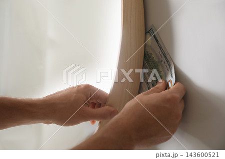 Man hiding money behind mirror indoors, closeup. Financial savings Man hiding money behind mirror indoors, closeup. Financial savings 143600521