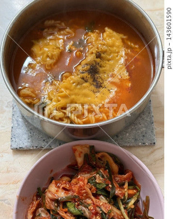 Steaming hot ramyun with rich, savory broth and chewy noodles, paired with spicy, tangy kimchi. A perfect Korean comfort food combination, balancing bold flavors and satisfying textures. 143601590