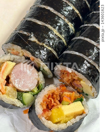 Delicious kimbap rolls filled with fresh vegetables, seasoned rice, and savory proteins, all wrapped in crisp seaweed. A perfect combination of flavor and texture in every bite. 143601623