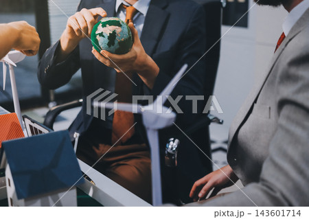 Team presenting a solar and wind energy project with model house, earth globe and green ideas in an office meeting Team presenting a solar and wind energy project with model house, earth globe and green ideas in an office meeting 143601714