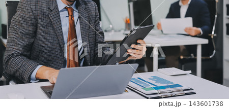 Business team collaborating on digital data analysis in modern office Business team collaborating on digital data analysis in modern office 143601738