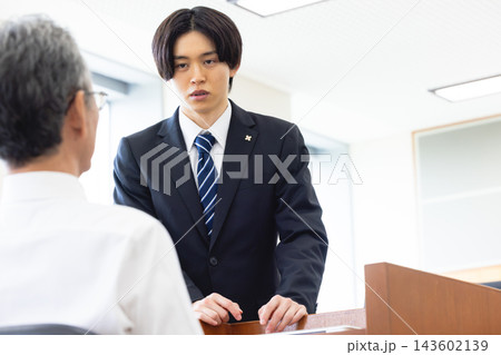 裁判所の法廷で男性に質問する若手男性検事 裁判所の法廷で男性に質問する若手男性検事 143602139