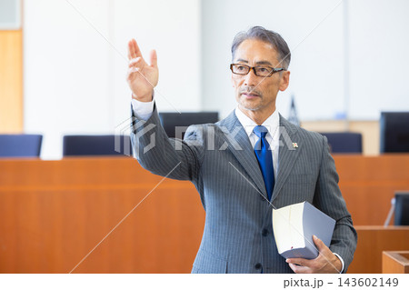法廷で手を挙げて発言するベテラン男性検事 法廷で手を挙げて発言するベテラン男性検事 143602149