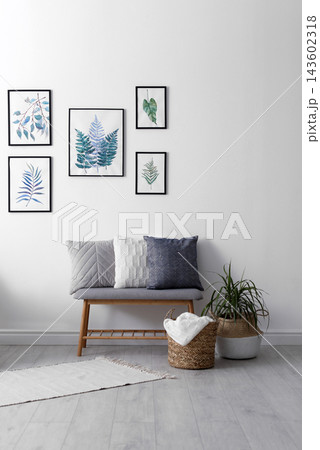 Beautiful paintings of tropical leaves on white wall in living room interior 143602318