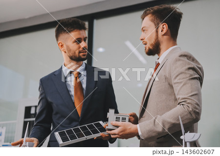 Team presenting a solar and wind energy project with model house, earth globe and green ideas in an office meeting 143602607